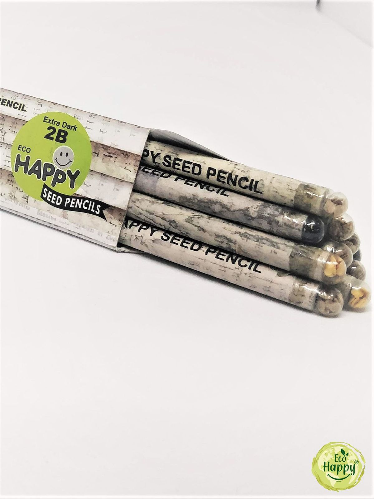 Four boxes of Eco Happy newspaper seed pencils fanned out on a cream cloth, seed capsules visible at the pencil tips