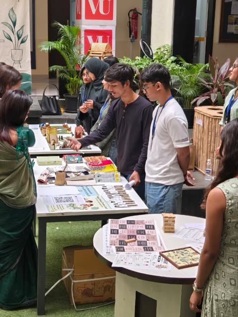 Visitors browsing the Eco Happy stall of newspaper stationery and seed products at a campus exhibition